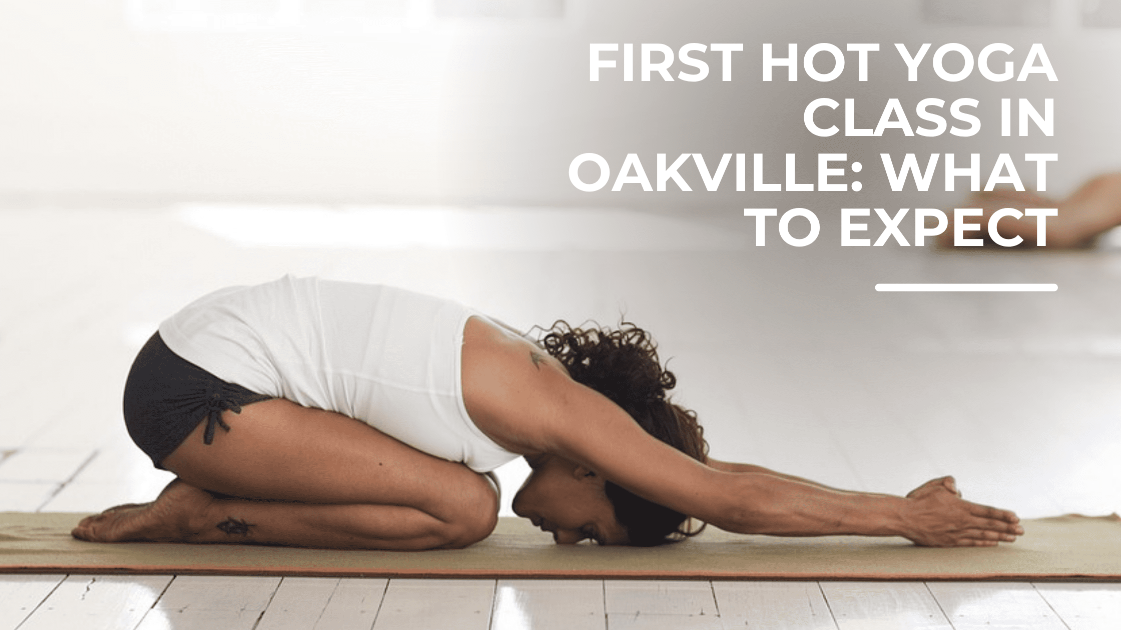 Person resting in child’s pose on a yoga mat in a bright studio, with text overlay “First hot yoga class in Oakville: what to expect.”